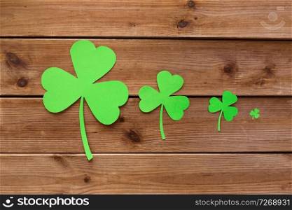 fortune, luck and st patricks day concept - green paper shamrocks on wooden background. green paper shamrocks on wooden background