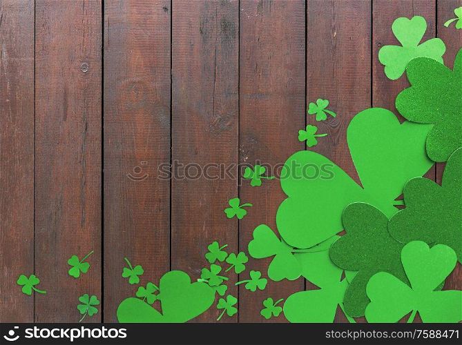 fortune, luck and st patricks day concept - green paper shamrocks on wooden background. green paper shamrocks on wooden background