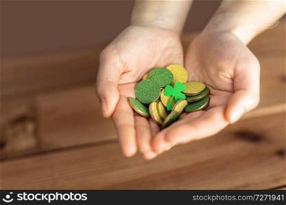 fortune, luck and st patricks day concept - hands holding golden coins and shamrock leaf on wooden background. hands with golden coins and shamrock leaf