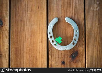 fortune, luck and st patricks day concept - horseshoe with shamrock on wooden background. horseshoe with shamrock on wooden background