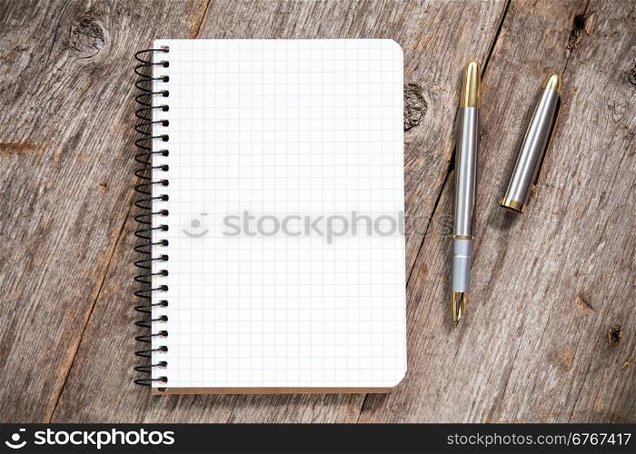 Fountain pen and notebook with square grid on wooden surface