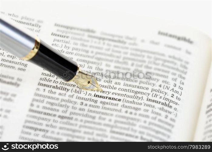 Fountain pen pointing to the word &rsquo;insurance&rsquo; on the page of a generic dictionary.