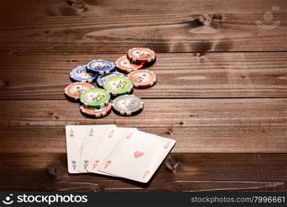 Four aces and chips, vintage poker game playing cards on a wood table