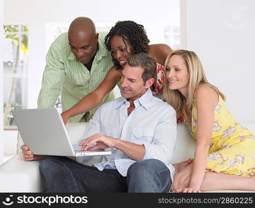 Four adults on sofa looking at laptop