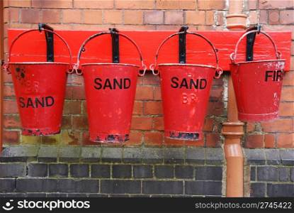 four antique fire buckets on hooks at a train station (brick wall background)