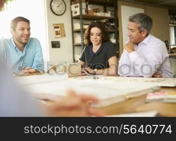Four Architects Sitting Around Table Having Meeting