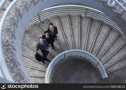 Four business associates standing on spiral staircase, portrait