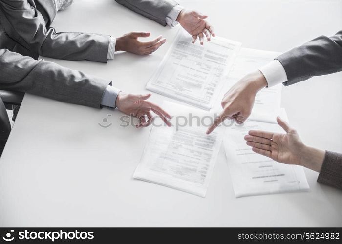 Four business people arguing and gesturing around a table during a business meeting, hands only