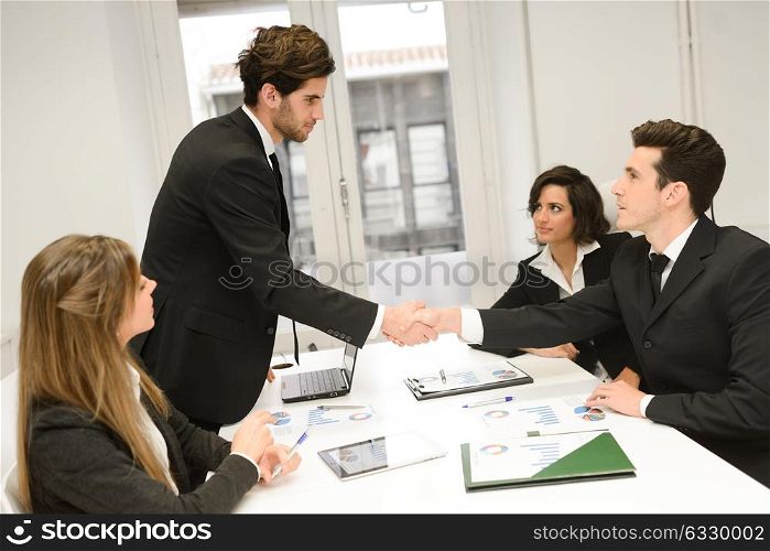 Four business people shaking hands, finishing up a meeting