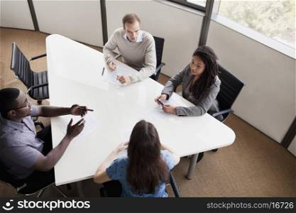 Four business people sitting at a conference table and discussing during a business meeting