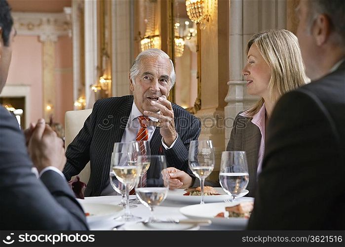 Four business people sitting at restaurant table talking