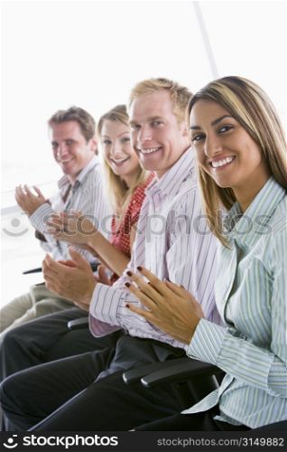 Four businesspeople applauding indoors smiling