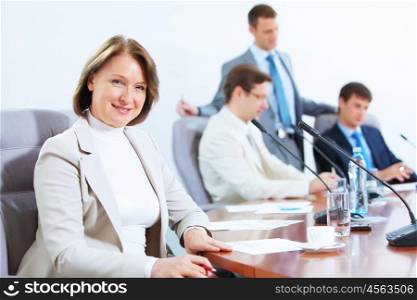 Four businesspeople at meeting. Image of businesswoman at business meeting with three businessmen in background