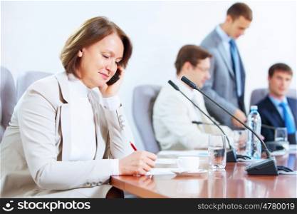 Four businesspeople at meeting. Image of businesswoman at business meeting with three businessmen in background