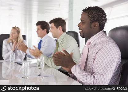 Four businesspeople in a boardroom applauding