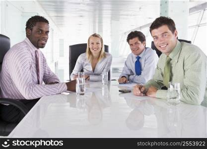 Four businesspeople in a boardroom smiling