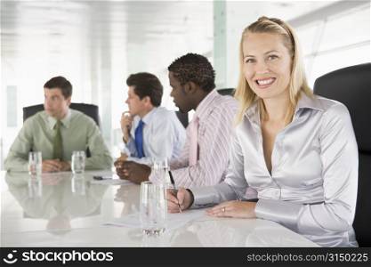 Four businesspeople in a boardroom smiling