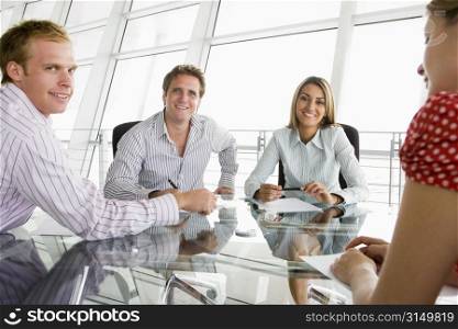 Four businesspeople in a boardroom with paperwork smiling