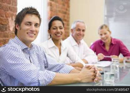 Four businesspeople in boardroom smiling