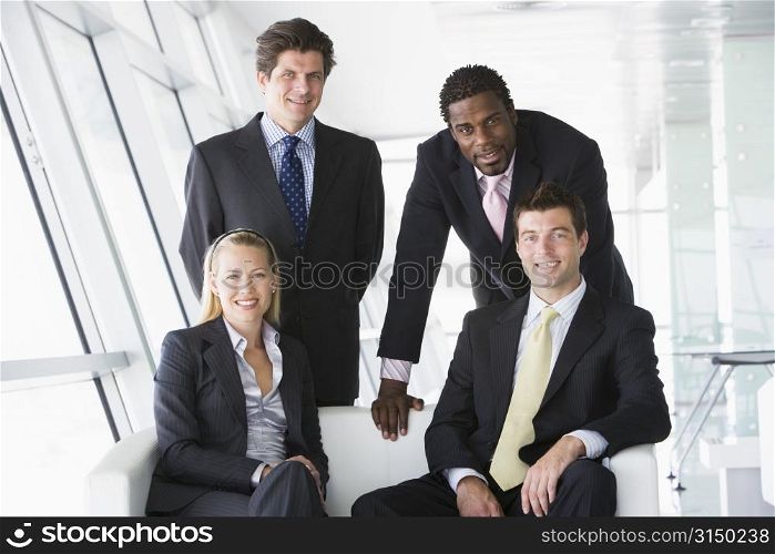 Four businesspeople in office lobby smiling