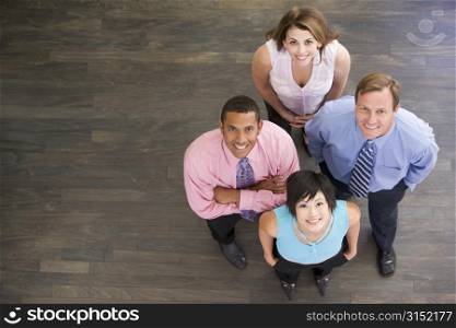 Four businesspeople standing indoors smiling