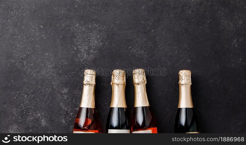 Four champagne bottles on dark background, flat lay, celebration concept. Four champagne bottles on dark background, flat lay