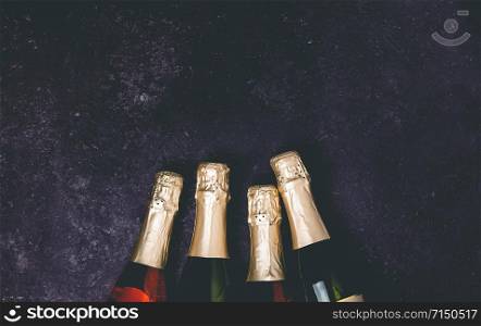 Four champagne bottles on dark background, flat lay, celebration concept