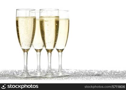 Four champagne glasses and silver shiny glitters isolated on white background