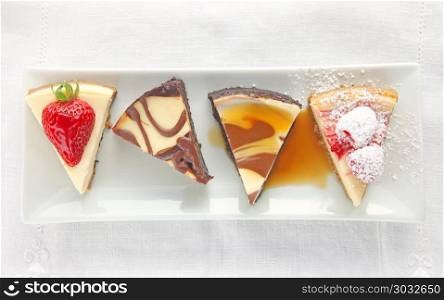 Four cheesecake portions topped with fresh berries, chocolate and caramel sauce. Cheesecake slices with assorted toppings