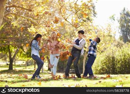 Four Children Throwing Autumn Leaves In The Air