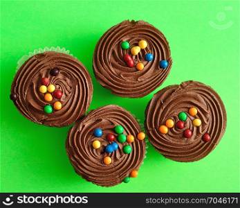 Four chocolate cupcakes isolated on a green background