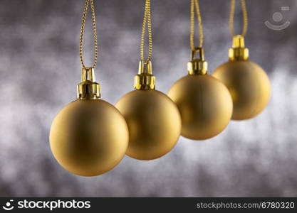 Four christmas decoration ball hanging against a silver glitter background with shallow depth of Field