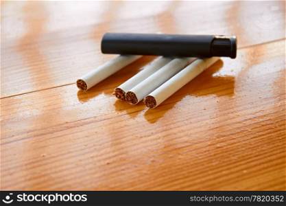 Four cigarettes and lighter on the lacquered wooden table