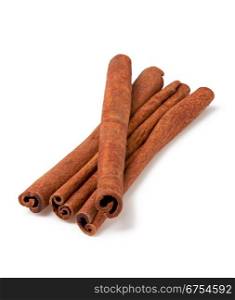 four cinnamon sticks stacked on white background