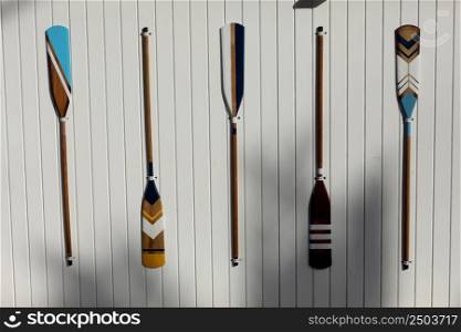 four colourful wooden paddles hangs on a white wall. canoe oars for active water sport. holiday vacation. High quality photo.. four colourful wooden paddles hangs on a white wall. canoe oars for active water sport. holiday vacation. High quality photo