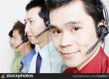 Four customer service representatives talking on headsets