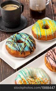 Four different donuts with coffee on wooden table