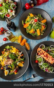 Four different types of salads served freshly on blue stone table