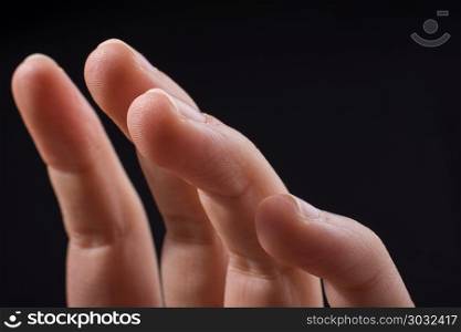 Four fingers of a human hand partly seen in view. Four fingers of a child hand partly seen in black background