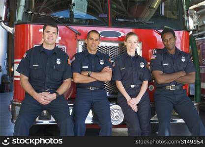 Four firefighters leaning on fire engine