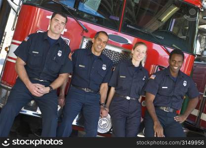 Four firefighters leaning on fire engine