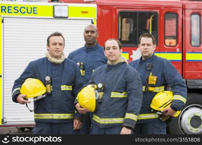 Four firefighters standing by fire engine