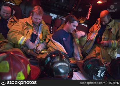 Four firemen in fire engine putting on gear (blur)