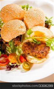 four fresh and delicious mini chicken burgers on a plate ,close up