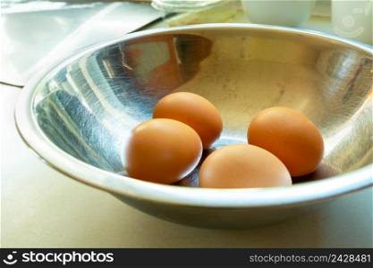 Four fresh chicken eggs in an aluminum bowl