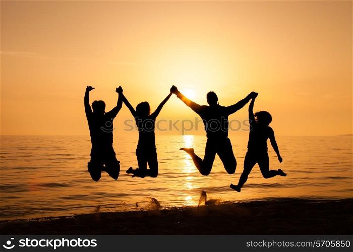Four friends jumping on the beach at sunset&#xA;