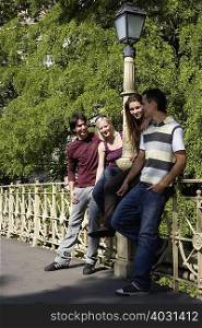 Four friends leaning on bridge rail