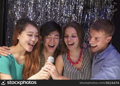 Four friends singing together at karaoke