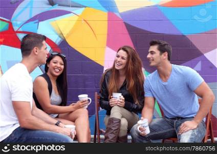 Four friends sitting together during a brake drinking coffee.