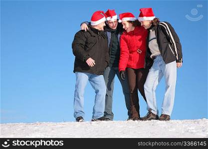 four friends talk on snow in santa claus hats